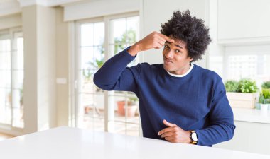Genç Afro-Amerikan erkek, günlük kazak giyip evde oturuyor. Alnındaki sivilceden mutsuz olduğunu gösteriyor. Siyah nokta enfeksiyonu. Sivilce ve deri problemi