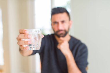Yakışıklı İspanyol adam su ciddi yüz soru hakkında düşünme taze bir bardak içme, çok karışık bir fikir
