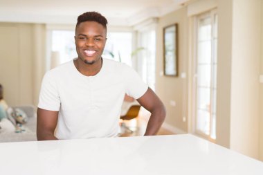 Evde beyaz masada Afro-Amerikan yakışıklı ile mutlu bir ve serin yüzündeki gülümseme. Şanslı kişi.
