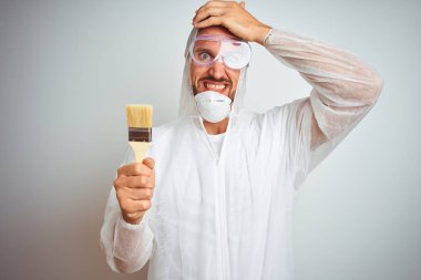 İzole edilmiş arka planda çalışan profesyonel işçi ekipmanı giyen ressam el üstünde tutulmuş, utanç ve şaşkınlık dolu, sinirli ve hayal kırıklığına uğramış bir yüz ifadesiyle stresli. Hata için korku ve üzüntü.