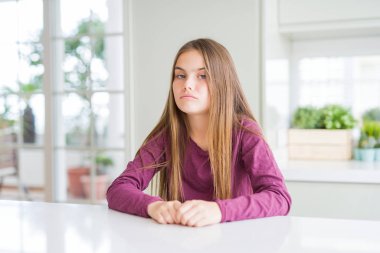 Beautiful young girl kid on white table depressed and worry for distress, crying angry and afraid. Sad expression.