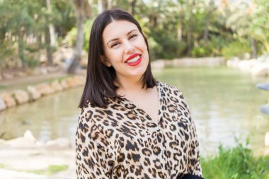 Bahçede mutlu gülümseyen kırmızı dudaklı genç güzel kadın