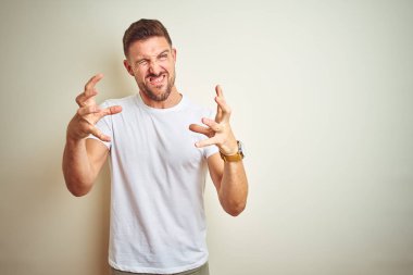İzole arka plan üzerinde Casual beyaz t-shirt giyen genç yakışıklı adam öfke ile sinirli çığlık, eller boğmaya çalışıyor, deli bağırarak
