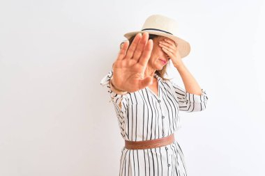 Orta yaşlı iş kadını çizgili elbise ve şapkalı, izole edilmiş beyaz arka planda, gözleri ellerle kaplayan ve üzgün ve korku ifadeleriyle jest yapmayı kesen biri. Utanç verici ve olumsuz bir kavram..