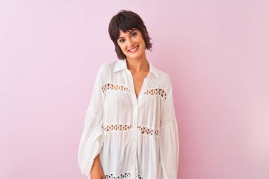 Yaz beyazı tişört giyen genç ve güzel bir kadın pembe arka planda mutlu ve serin bir gülümsemeyle dikiliyor. Şanslı kişi..