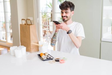 Genç adam alma fotoğraf ile Smartphone arasında Suşi Asya gıda fr