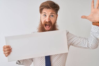 Genç kızıl saçlı İrlandalı adam izole edilmiş beyaz arka planda duruyor mutlu ve heyecanlı, kazanan yüz ifadesi zaferi büyük bir gülümsemeyle kutluyor ve ellerini kaldırıyor