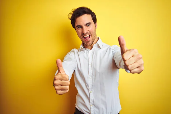 孤立した黄色の背景の上に立ってエレガントなシャツを着て若いハンサムなビジネスマンは 手で積極的なジェスチャーを行うことを承認し 親指を笑顔と成功のために幸せ 勝者のジェスチャー — ストック写真