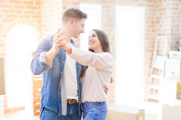 Beautiful young couple having fun dancing at new apartment, cele