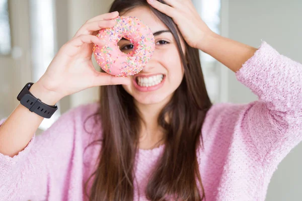 ピンクのチョコチップを食べる美しい若い女性ドーナツは 頭の上に手でストレスを与え 恥と驚きの顔でショックを受け 怒りとイライラしました 間違いに対する恐怖と動揺 — ストック写真