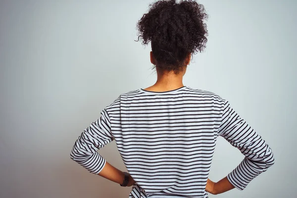 African american woman wearing navy striped t-shirt standing over isolated white background standing backwards looking away with arms on body