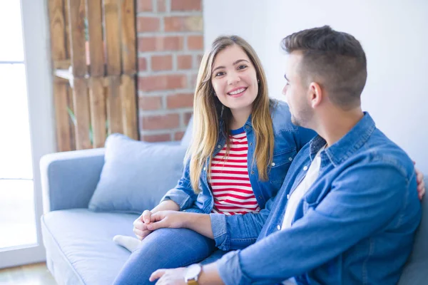 Junges schönes Paar sitzt verliebt umarmt auf dem Sofa bei ho — Stockfoto