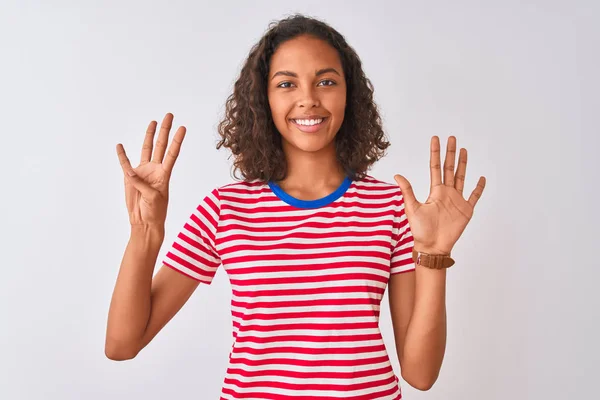 赤のストライプのTシャツを着た若いブラジル人女性が 自信を持って幸せな笑顔で指の数9を見せ 指差す白い背景の上に立って — ストック写真