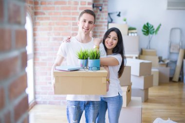 Young beautiful couple sitting on the floor at new home around cardboard boxes skeptic and nervous, disapproving expression on face with crossed arms. Negative person.
