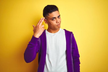 Mor eşofman üstü giyen genç Brezilyalı adam izole edilmiş sarı arka planda duruyor. Kendini vuruyor ve öldürüyor..