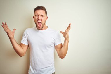 Yakışıklı delikanlı deli ve silah ile başarı için deli kutluyor izole arka plan üzerinde rahat beyaz t-shirt giyen kaldırdı ve heyecanlı çığlık gözler kapalı. Kazanan kavramı