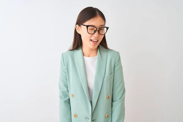 Chinese businesswoman wearing elegant jacket and glasses over isolated white background winking looking at the camera with sexy expression, cheerful and happy face.