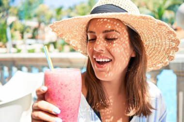 Güzel bir kadın oteldeki barın havuzunda oturmuş yaz tatili için sağlıklı meyve suyu içiyor.