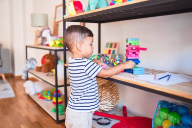 Güzel çocuk anaokulunda ahşap bloklarla oynuyor.