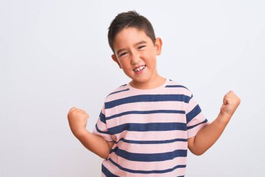Güzel çocuk, izole edilmiş beyaz arka plan üzerinde sıradan çizgili tişört giymiş mutlu ve heyecanlı bir şekilde kollarını kaldırıp, gülümseyerek ve başarı için çığlık atarak kazanan jestler yapıyor. Kutlama konsepti.