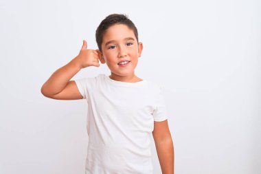 Güzel çocuk, izole edilmiş beyaz arka planda tişört giyip telefonda el ve parmak hareketleriyle gülümsüyor, telefonda konuşuyor gibi. İletişim kavramları.