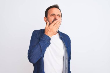 İzole edilmiş beyaz arka planda duran mavi kot gömlek giyen orta yaşlı yakışıklı adam ağzıyla esnemekten sıkılmış. Huzursuz ve uykulu..