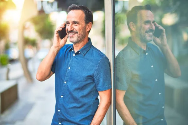 中年ハンサムなビジネスマンが路上で話しているスマートフォンの笑顔 — ストック写真
