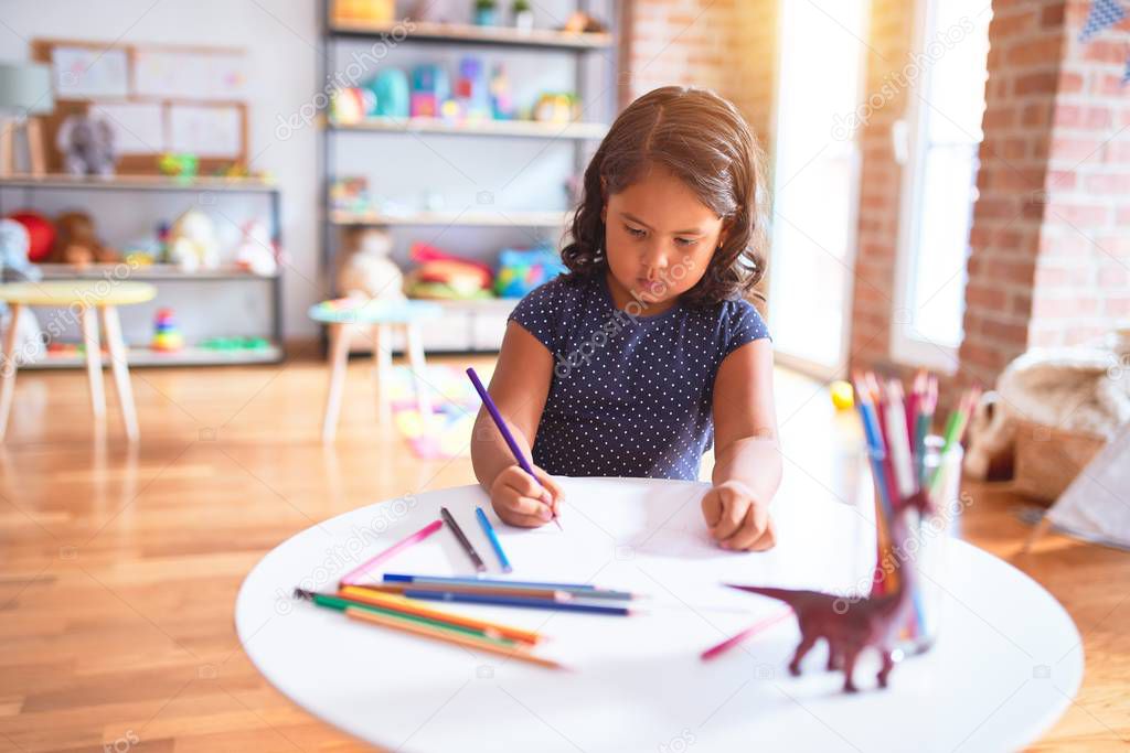 Beautiful toddler girl drawing cute draw using colored pencils at kindergarten