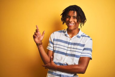 Sarı arka plan üzerinde çizgili tişört giyen Afro-Amerikan bir adam. Yüzünde kocaman bir gülümseme, eli ve parmağı kameraya bakıyor..