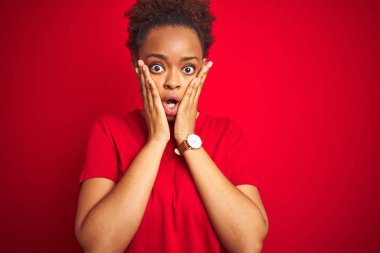 Afro saçlı, genç, güzel, afro saçlı, kırmızı arka planda korkmuş ve şok olmuş, şaşırmış ve şaşırmış bir şekilde yüzü olan bir Amerikalı kadın.
