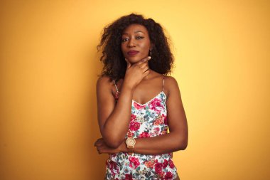 Sarı arka plan üzerinde çiçekli tişört giyen Afro-Amerikalı kadın kameraya kollarını kavuşturup gülümseyerek bakıyor ve çenesini kaldırıyor. Olumlu düşünüyorum..