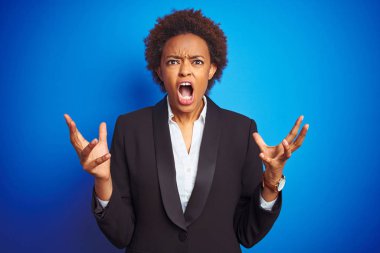 Izole mavi arka plan üzerinde Afro-Amerikan iş yönetici kadın deli ve deli bağırarak ve agresif ifade ve kollar kaldırdı ile bağırıyor. Hayal kırıklığı kavramı.