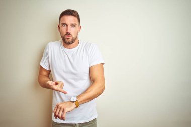 Acele işaretleme izlemek için zaman, sabırsızlık, üzgün ve kızgın son tarih gecikme için izole arka plan üzerinde rahat beyaz t-shirt giyen genç yakışıklı adam