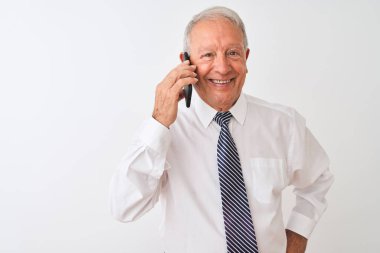 Üst düzey gri saçlı işadamı, izole edilmiş beyaz arka planda, gülen bir yüzle, dişlerini gösteren kendine güvenen bir gülümsemeyle akıllı telefondan konuşuyor.