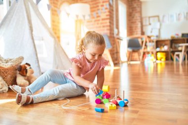 Güzel sarışın küçük kız anaokulunda trenle oynuyor.