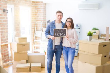 Güzel genç çift aşık ve yeni bir ev için mutlu gülümseyen yeni bir eve hareketli tahta tutarak sarılmak