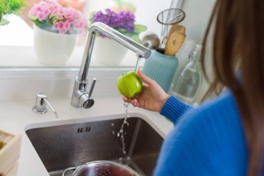 Genç kadın lavabo su kullanarak sebze ve meyve yıkama
