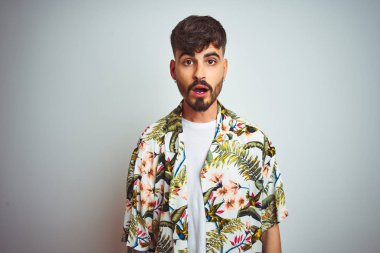 Tatilde dövmeli bir adam izole edilmiş beyaz arka plan üzerinde duran korku, korku ve heyecan dolu bir yüz ifadesinden korkan ve şok olan bir adam..