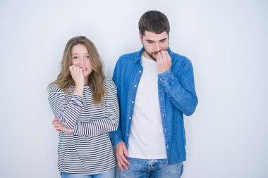 Beyaz izole arka plan üzerinde birlikte ayakta genç güzel çift vurguladı ve ağız ısırma çivi elleri ile sinir bakıyor. Anksiyete sorunu.