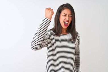 Genç, çizgili tişört giyen güzel Çinli kadın izole edilmiş beyaz arka planda kızgın ve kızgın duruyor öfkeyle bağırırken yumruğunu kaldırıyor. Öfke ve agresif kavram.