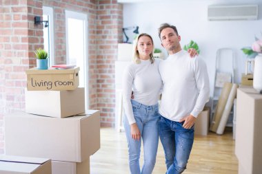 Genç ve güzel bir çift, yeni evlerinde karton kutuların etrafında dikiliyorlar. Yüzlerinde ciddi bir ifade var. Basit ve doğal bir şekilde kameraya bakıyorsun..