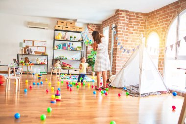 Anaokulunda renkli toplarla oynayan genç ve güzel bir öğretmen ve çocuk.