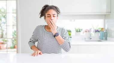 Afro saçlı, sıradan çizgili kazak giyen, esnemekten sıkılmış, ağzı eliyle kapatan güzel Afro-Amerikan kadını. Huzursuz ve uykulu..