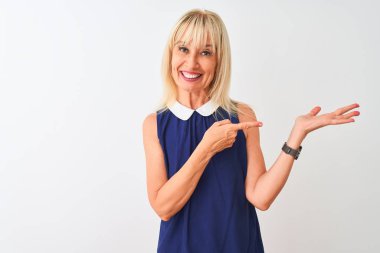 Soyutlanmış beyaz arka plan üzerinde duran zarif mavi elbiseler giyen orta yaşlı kadın kameraya hayret ediyor ve gülümsüyor..