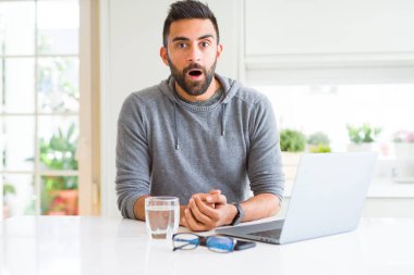 Yakışıklı İspanyol, bilgisayar bilgisayarı kullanıyor. Şaşırmış ve korkmuş bir ifade, korku ve heyecanlı bir yüz..