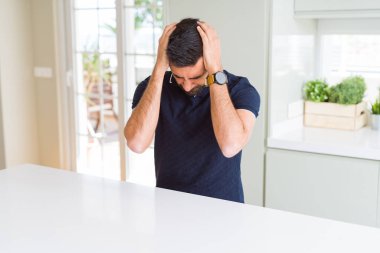 Evde yakışıklı İspanyol adam baş ağrısı umutsuz muzdarip ve stresli çünkü ağrı ve migren. Eller baş üstünde.