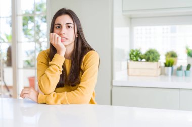 Sarı kazak giyen güzel genç kadın vurgulandı ve ağız ısırma tırnakları ile gergin bakıyor. Anksiyete sorunu.