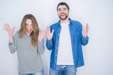 Genç ve güzel bir çift, beyaz soyutlanmış arka planda bir arada durup çılgın ve başarıyı kollarını kaldırıp heyecanla haykırarak kutluyor. Kazanan konsept