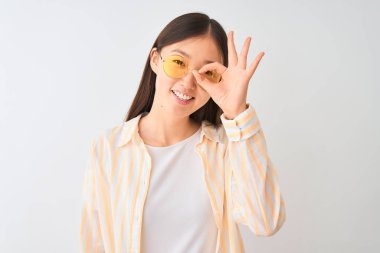 Genç Çinli kadın çizgili gömlek ve gözlük takıyor. İzole edilmiş beyaz arka plan, gülümsüyor. Tamam.