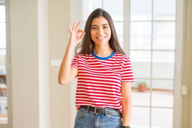 El ve parmak ile ok işareti yapıyor olumlu gülümseyen rahat t-shirt giyen genç güzel kadın. Başarılı ifade.